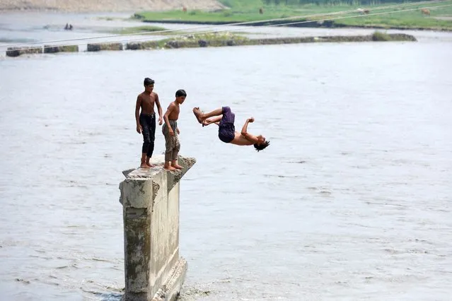 Boys jump into the Naguman River while taking a bath to cool off amid hot weather in Naguman, on the outskirts of Peshawar, Pakistan on July 27, 2023. (Photo by Fayaz Aziz/Reuters)