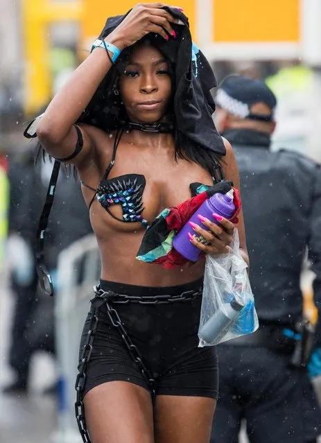 One woman tries to shelter from the strong winds and heavy rain during the Notting Hill Carnival in London, Britain on August 26, 2018. (Photo by London News Pictures)