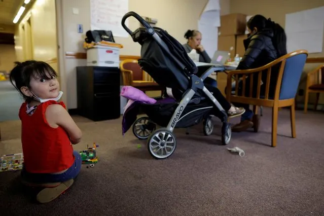 Five year-old Lucia plays with toys while Elizabeth Dejesus helps her mother apply for rental payment assistance at La Colaborativa, which offers housing and rental assistance amid the coronavirus disease (COVID-19) pandemic, in Chelsea, Massachusetts, U.S., May 4, 2021. (Photo by Brian Snyder/Reuters)