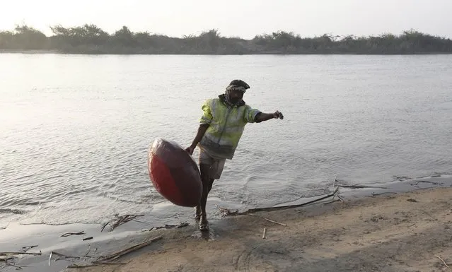 A man walks out of the water with the floating pitcher he uses to catch fish in Soneri village next to Keenjhar Lake, near Thatta, February 22, 2015. (Photo by Akhtar Soomro/Reuters)