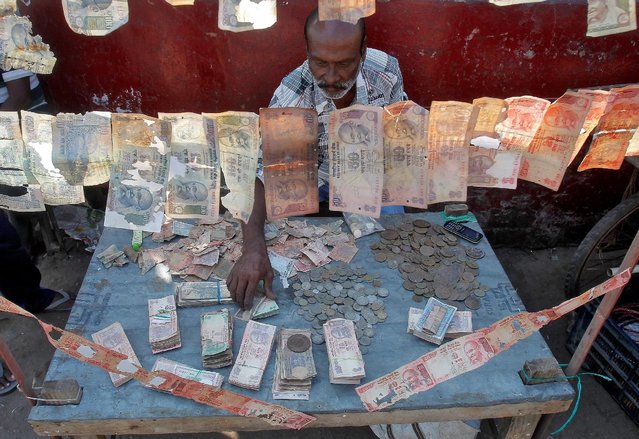 A roadside currency exchange vendor sorts Indian currency notes at his stall in Agartala, India, December 6, 2016. (Photo by Jayanta Dey/Reuters)