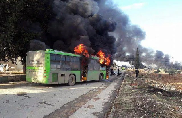 In this photo released by the Syrian official news agency SANA, smoke rises in green government buses, in Idlib province, Syria, Sunday, December 18, 2016. Activists said, militants have burned at least five buses assigned to evacuate wounded and sick people from two villages in northern Syria. The incident could scuttle a wider deal that encompasses the evacuation of thousands of trapped rebel fighters and civilians from the last opposition foothold in east Aleppo. (Photo by SANA via AP Photo)
