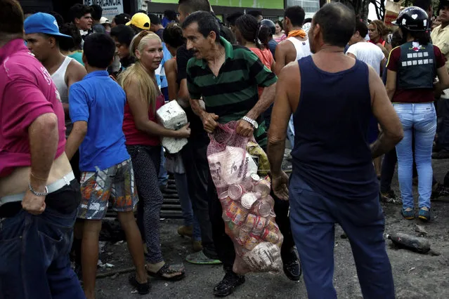 People carry goods taken from a food wholesaler after it was broken into, in La Fria, Venezuela December 17, 2016. (Photo by Carlos Eduardo Ramirez/Reuters)