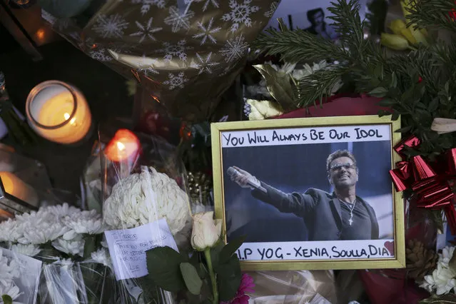 A photograph of British singer George Michael is seen among floral tributes and candles outside Michael's north London home on December 26, 2016, after news of the singer's death broke. Tributes poured in from the music world on December 26 after British pop superstar George Michael, who rose to fame with the duo Wham! and a string of smash hits including “Last Christmas”, died aged 53. Michael died of apparent heart failure on Christmas Day at his home in Goring, a village on the River Thames in Oxfordshire, west of London, after an award-winning career spanning more than three decades. (Photo by Daniel Leal-Olivas/AFP Photo)