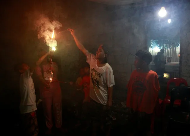 Neighbours light sparklers next to the house of Sonny Espinosa, 15, whose relatives (R) are grieving after he was shot dead in a drug related vigilante execution, during New Year's Eve in Caloocan city, Metro Manila, Philippines January 1, 2017. (Photo by Czar Dancel/Reuters)