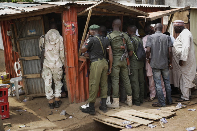 Nigerian policemen gather around a shop with a television set in Kaduna, Nigeria on Monday, March 30, 2015, to watch the beginning of the live broadcast of the collation of votes for last Saturday's elections. (Photo by Jerome Delay/AP Photo)