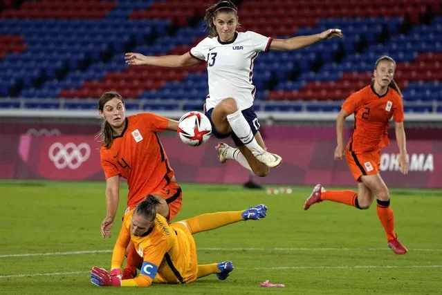 United States' Alex Morgan jumps over Netherlands' goalkeeper Sari van Veenendaal as she attempts to score during a women's quarterfinal soccer match at the 2020 Summer Olympics, Friday, July 30, 2021, in Yokohama, Japan. (Photo by Kiichiro Sato/AP Photo)