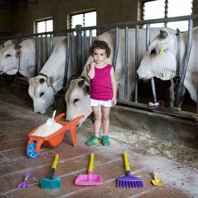 Alessia – Castiglion Fiorentino, Italy. Alessia was born and raised in the country, his family owns one of the largest farms in the city. She loves to play with animals and helping her grandfather with the work of the farm. With her small tools she brings food to the many Chianina cows. “Toy Stories” project. (Gabriele Galimberti)