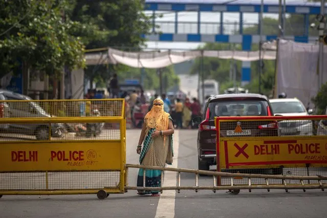 A woman stands on a road blocked by protesters at a demonstration site outside a crematorium where a 9-year-old girl from the lowest rung of India's caste system was, according to her parents and protesters, raped and killed earlier this week, in New Delhi, India, Thursday, August 5, 2021. (Photo by Altaf Qadri/AP Photo)