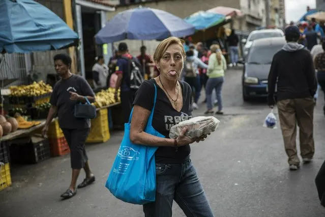 A woman sticks out her tongue as she shops at the Quinta Crespo street market in downtown Caracas, Venezuela, Saturday, January 26, 2019. The country's political showdown moves to the United Nations Saturday where a Security Council meeting called by the United States will pit backers of President Nicolas Maduro against the Trump administration and supporters of the country's self-declared interim leader Juan Guaido. (Photo by Rodrigo Abd/AP Photo)