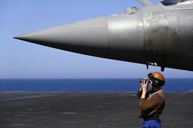 A French marine stands past the nose of a French air force Rafale jet fighter parked on the UK Royal Navy's aircraft carrier HMS Queen Elizabeth during the Navy exercise “Gallic strike” off the coast of Toulon, south-eastern France on June 3, 2021. This unprecedented joint maneuver called “Gallic Strike”, which has mobilized since two days 14 warships and 56 combat aircraft off the coast of Toulon, aims in particular to train to conduct strikes from the sea, and to operate jointly the tricolor Rafale Marine fighter planes, catapulted, and the British F-35s which take off vertically or using a springboard. (Photo by Christophe Simon/AFP Photo)