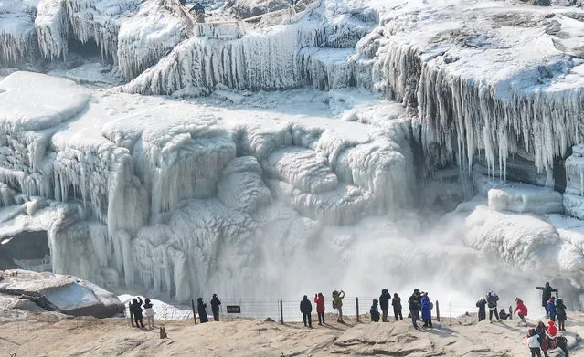 Tourists view Hukou Waterfall on the Yellow River in the frigid winter on December 28, 2023 in Yan'an, Shaanxi Province of China. Freezing winter air has turned Hukou Waterfall into an icy wonderland. (Photo by VCG/VCG via Getty Images)