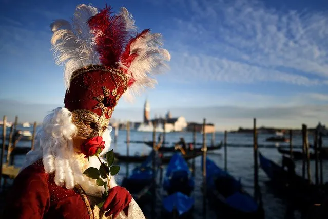 A reveller wearing a mask and a period costume smells a rose as he takes part in the Venice Carnival on February 24, 2019 in Venice. (Photo by Alberto Pizzoli/AFP Photo)