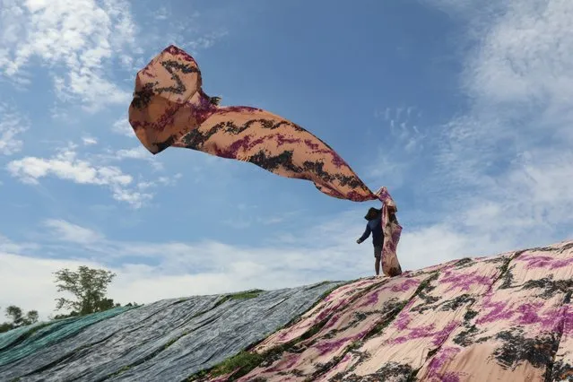 A worker arranges fabric known locally as “beach fabric”, used to make Muslim women's garments, to dry on a riverbank in Surakarta, Central Java, on January 4, 2024. (Photo by Garry Lotulung/AFP Photo)