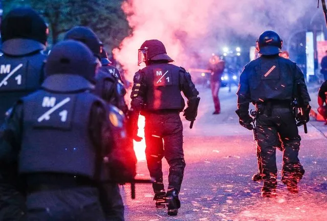 In this May 1, 2015 photo riot police officers walk pass flares during a May Day demonstration in Hamburg, Germany. (Photo by Markus Scholz/AP Photo/DPA)