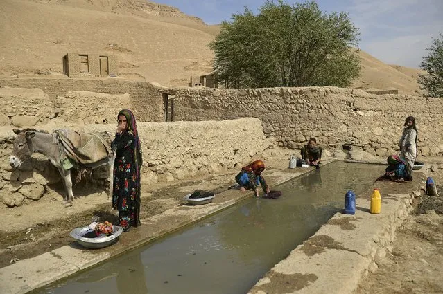 This picture taken on October 15, 2021 shows children washing clothes in Bala Murghab district of Badghis province. Drought stalks the parched fields around the remote Afghan district of Bala Murghab, where climate change is proving a deadlier foe than the country's recent conflicts. (Photo by Hoshang Hashimi/AFP Photo)