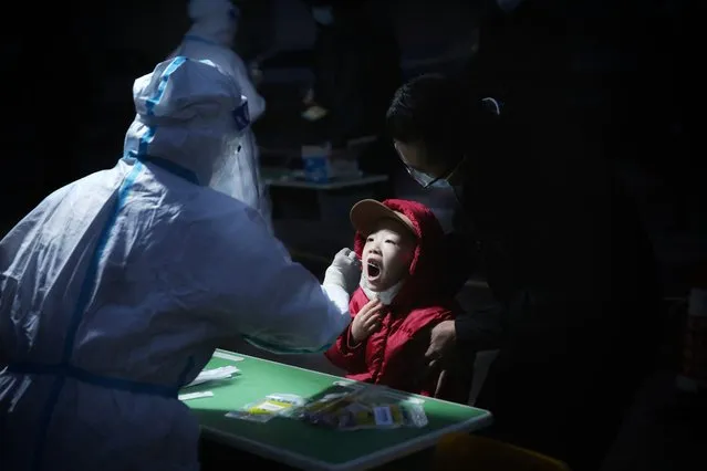 Medical staff take a swab sample from a child to be tested for the Covid-19 coronavirus in Ganzhou District in Zhangye, in China's northwest Gansu province early on October 29, 2021. (Photo by AFP Photo/China Stringer Network)