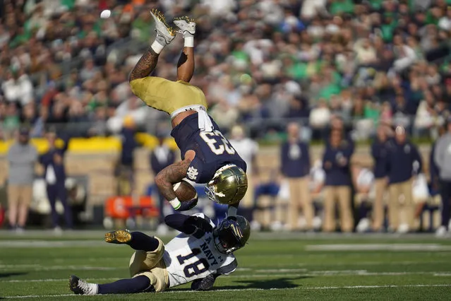 Navy safety Rayuan Lane (18) upends Notre Dame running back Kyren Williams (23) in the first half of an NCAA college football game in South Bend, Ind., Saturday, November 6, 2021. (Photo by Paul Sancya/AP Photo)