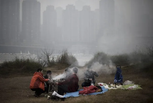 In this photo taken Sunday February 23, 2014, residents barbecue along the river bank during a hazy day in southwest China's Chongqing municipality. Xinhua said that almost all provinces in central and east China have had serious air pollution since Friday, and that Beijing and five provinces in northern and eastern China had reported “severe smog”. (Photo by AP Photo)