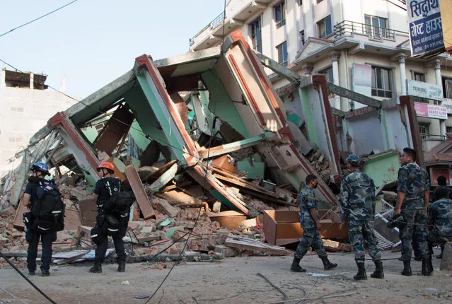 Rescue workers stand beside a building that collapsed in an earthquake in Kathmandu, Nepal, Tuesday, May 12, 2015. (Photo by Ranup Shrestha/AP Photo)