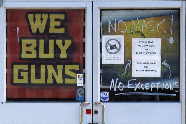 A sign on the door warning customers not to wear a face mask reads “We Draw Guns on Masked Visitors” at the 619DW Guns and Ammo store amid the coronavirus disease (COVID-19) pandemic in Merrimack, New Hampshire, U.S., November 29, 2021. (Photo by Brian Snyder/Reuters)