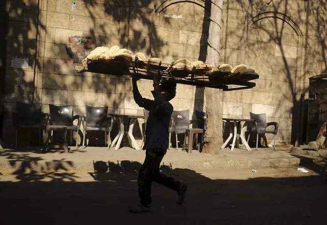 A bakery worker carries freshly baked bread on his head to deliver it to shops in Cairo, Egypt, February 14, 2016. (Photo by Asmaa Waguih/Reuters)