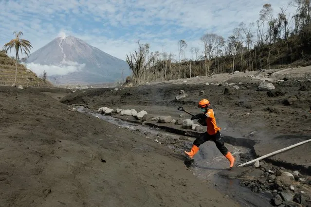 A rescue worked jumps across the lava flow path during an operation at an area affected by the eruption of Mount Semeru volcano, in Curah Kobokan, Pronojiwo district, Lumajang, East Java province, Indonesia, December 8, 2021. (Photo by Willy Kurniawan/Reuters)