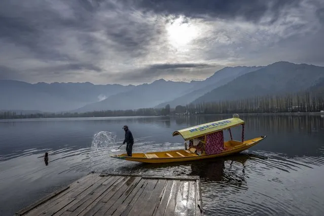 A Kashmiri boatman sprays water with his paddle to clean a wooden jetty early morning in Srinagar, Indian controlled Kashmir, Wednesday, April 3, 2024. (Photo by Dar Yasin/AP Photo)