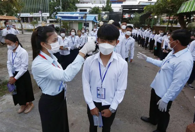 A student has his temperature checked as he arrives at a venue prior to a grade 12 exam at a school in Phnom Penh, Cambodia, 27 December 2021. The Ministry of Education, Youth and Sports required all grade 12 students to have temperature checks one day before the exam and wearing the necessary protective masks during the examinations in order to prevent the spread of the fast-spreading Covid-19 Omicron variant. (Photo by Mak Remissa/EPA/EFE)