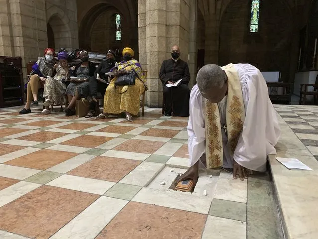 In this photo provided by Oryx Media, Anglican Archbishop Thabo Makgoba lays the ashes of Archbishop Emeritus Desmond Tutu to rest at the high altar of St. George's Cathedral, in Cape Town, South Africa. Sunday. January 2, 2022. Tutu died on Dec. 26, at age 90. At back are members of the Tutu family and Dean Michael Weeder of the Cathedral. (Photo by Benny Gool/Oryx Media via AP Photo)