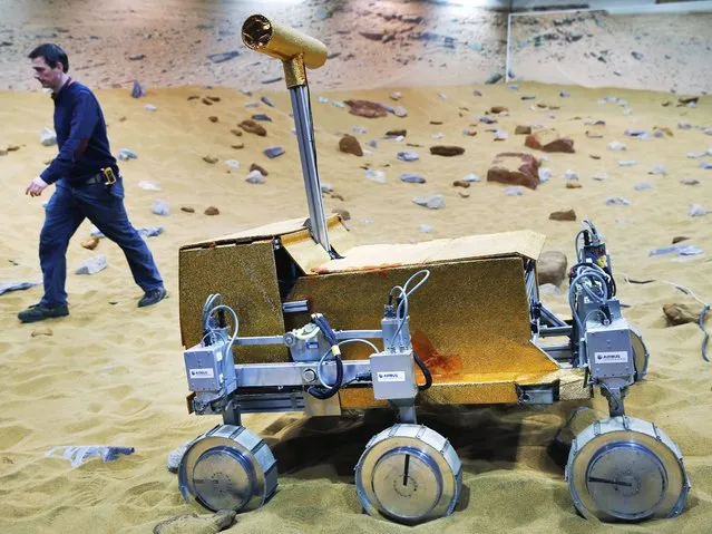 Engineer Ben Nye walks past a robotic vehicle on the “Mars Yard Test Area”, a testing ground for the robotic vehicles of the European Space Agency’s ExoMars program scheduled for 2018, in Stevenage, England, Thursday, March 27, 2014. It looks like a giant sandbox – except the sand has a reddish tint and the “toys” on display are very expensive prototypes designed to withstand the rigors of landing on Mars. (Photo by Lefteris Pitarakis/AP Photo)