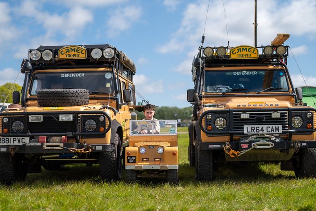 Huw Williams, 10, drives a modified electric mobility scooter, converted into a mini mk2 Land Rover, in the Camel Trophy colours, as he passes between two full size Defenders in the same livery, during the Great British Land Rover Show at the Bath & West Showground, Shepton Mallet, UK on Sunday, April 21, 2024. (Photo by Ben Birchall/PA Images via Getty Images)