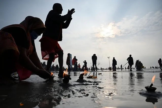 Pilgrims perform rituals as they pray at the beach during the Hindu religious festival of Gangasagar Mela on Sagar Island, some 150 kilometers south of Kolkata, West Bengal, on January 13, 2022. (Photo by Dibyangshu Sarkar/AFP Photo)