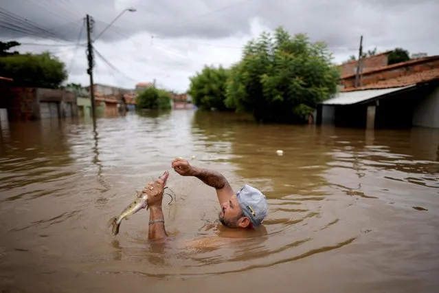 A man catches a fish in a street flooded during floods caused by heavy rain in Imperatriz, Maranhao state, Brazil on January 6, 2022. (Photo by Ueslei Marcelino/Reuters)