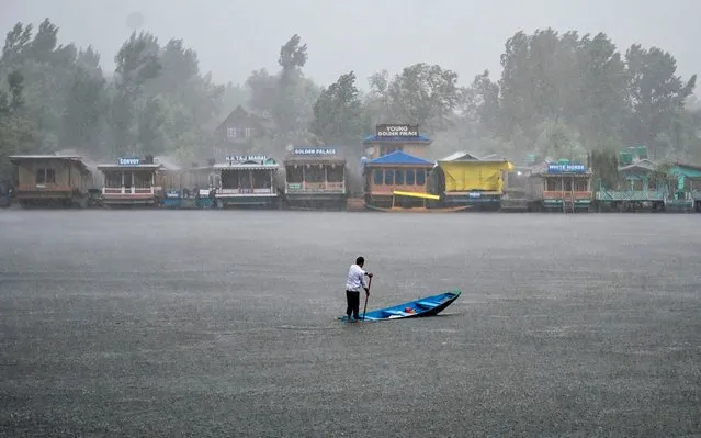 A resident rows a boat on the Dal Lake during a heavy rainfall in Srinagar on July 25, 2019. (Photo by Tauseef Mustafa/AFP Photo)