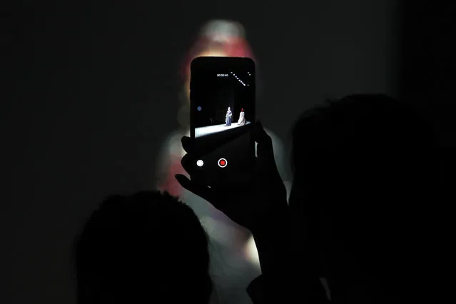 A spectator uses a smartphone to film models wearing creations by Tibetan designer Aj-Namo on stage during the China Fashion Week in Beijing, Thursday, March 30, 2017. (Photo by Andy Wong/AP Photo)