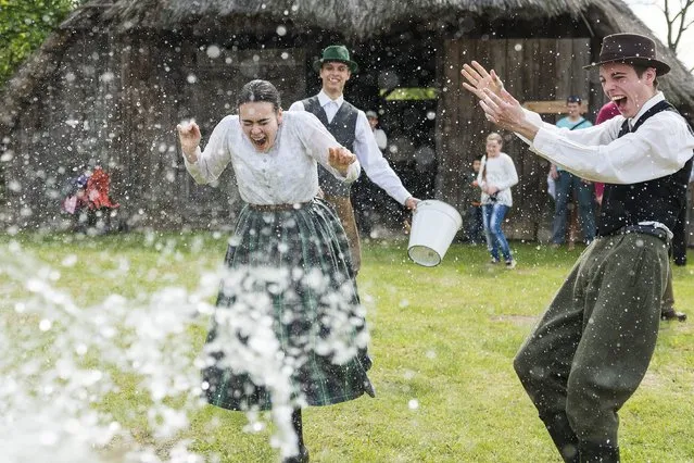 A woman in a traditional costume is sprayed with water by men as members of the Marghareta Dance Group perform Easter folk traditions of the region in the Museum Village in Nyiregyhaza, 227 kms northeast of Budapest, Hungary, Monday, April 21, 2014. (Photo by Attila Balazs/AP Photo/MTI)