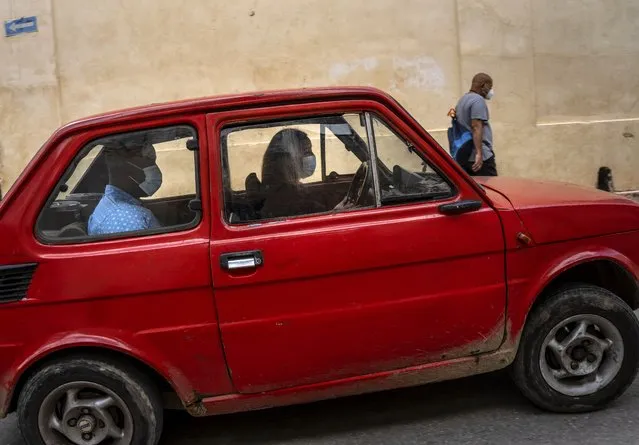 Wearing masks as a precaution against the spread of the new coronavirus, a woman drives a car in Havana, Cuba, Wednesday, February 16, 2022. (Photo by Ramon Espinosa/AP Photo)