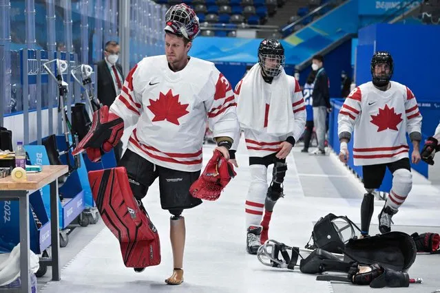 Canada's athletes walk with their prosthetic leg before the ice hockey preliminary round match between Canada and the US during the Beijing 2022 Winter Paralympic Games in Beijing on March 5, 2022. (Photo by Mohd Rasfan/AFP Photo)