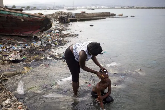 In this Sunday, March 17, 2019 photo, a woman bathes her daughter on the seashore as they get ready for church, at the Warf of Port Cite Soleil in Port-au-Prince, Haiti. (Photo by Dieu Nalio Chery/AP Photo)