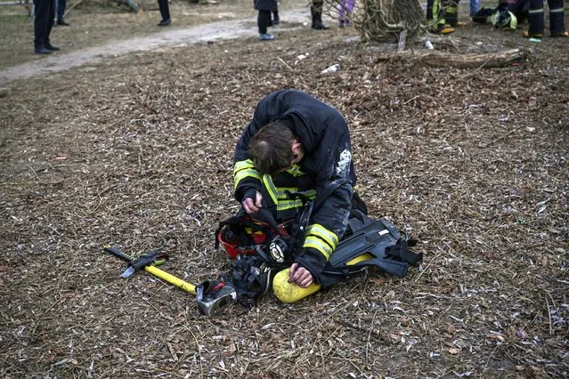 A fireman rests outside a burning apartment building in Kyiv on March 15, 2022, after strikes on residential areas killed at least two people, Ukraine emergency services said as Russian troops intensified their attacks on the Ukrainian capital. A series of powerful explosions rocked residential districts of Kyiv early today killing two people, just hours before talks between Ukraine and Russia were set to resume. (Photo by Aris Messinis/AFP Photo)