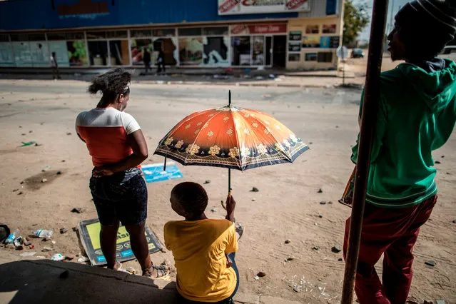 Residents look a the damages on the main street of Coligny, on April 26, 2017. The shops on the main street of the North Western Province town of Coligny were ransacked during a night of violence that erupted after a child from a nearby township died in unclear circumstances highlighting racial tensions in the area. (Photo by Marco Longari/AFP Photo)