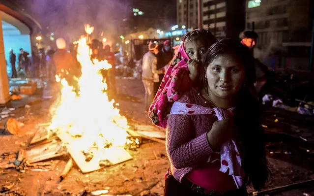 A woman and her daughter pose as indigenous people celebrate outside the Casa de la Cultura in Quito on October 13, 2019 after Ecuador's president and indigenous leaders reached an agreement to end violent protests. Ecuador's president and indigenous leaders reached an agreement to end nearly two weeks of violent protests against austerity measures put in place to obtain a multi-billion-dollar loan from the IMF. President Lenin Moreno met with Jaime Vargas, the head of the indigenous umbrella grouping CONAIE, for four hours of talks in the capital Quito broadcast live on state television. (Photo by Martin Bernetti/AFP Photo)