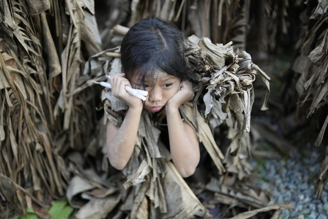 A young Catholic waits for the start of mass at the church of Saint John the Baptist during the mud festival at Bibiclat, Nueva Ecija province, northern Philippines, Monday, June 24, 2024. (Photo by Aaron Favila/AP Photo)