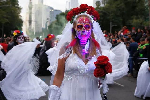 People dressed as Catrinas parade down Mexico City's iconic Reforma avenue during celebrations for the Day of the Dead in Mexico, City, Saturday, October 26, 2019. (Photo by Ginnette Riquelme/AP Photo)