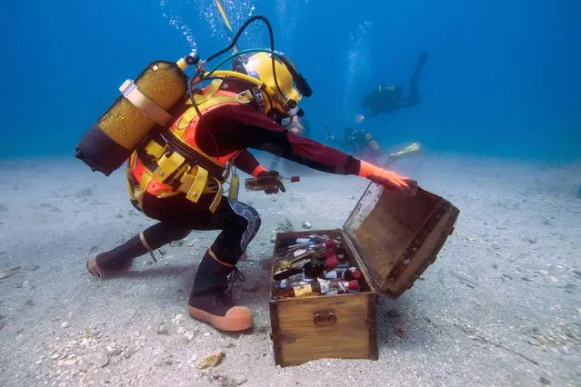 A diver takes wine bottles from an underwater trunk in the Mediterranean sea off Saint-Mandrier, southern France on May 15, 2017. Bandol wine matured undersea during one year before being analysed. (Photo by Boris Horvat/AFP Photo)