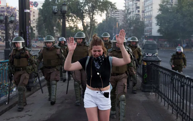 A woman cries while being escorted by police officers during an anti-government protest in Santiago, Chile, 07 November 2019. A proposed increase in the price of metro fares sparked a series of anti-government protests that have left at least 20 people dead. The protestors are demanding improvements in the quality of healthcare, education and general distribution of wealth in Chile. (Photo by Orlando Barría/EPA/EFE)