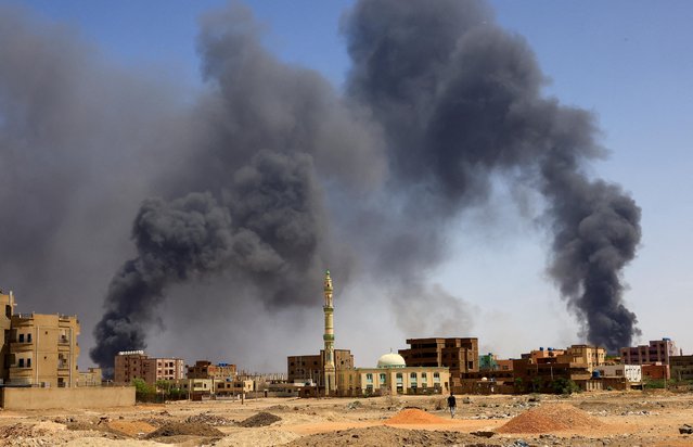 A man walks while smoke rises above buildings after aerial bombardment, during clashes between the paramilitary Rapid Support Forces and the army in Khartoum North, Sudan on May 1, 2023. (Photo by Mohamed Nureldin Abdallah/Reuters)