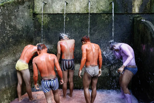 Young members of the village community wash the paint off their bodies at a holy spring after the Grebeg ritual on June 25, 2014 in Tegallalang Village, Gianyar, Bali, Indonesia. During the biannual ritual, young members of the community parade through the village with painted faces and bodies to ward off evil spirits. (Photo by Putu Sayoga/Getty Images)