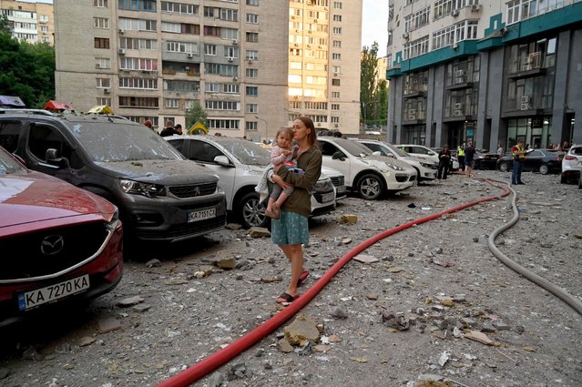 A local resident carries a baby outside a 24-storey building partially destroyed as a result of missiles strike in Ukrainian capital of Kyiv early on June 24, 2023. Ukraine was on high alert after a fresh barrage of Russian missiles on June 24, 2023, with casualties and damage reported in Kyiv and the central city of Dnipro. (Photo by Sergei Supinsky/AFP Photo)